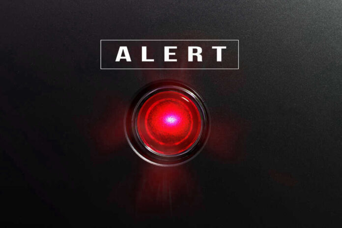 shutterstock_582441490 Red alert light against black background, text ALERT.