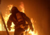 Inferno Swallows Spokane — 60,000 Flee Firefighter in full gear entering a burning building staircase