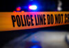 Buried Alive? Murder Case Takes Chilling Twist Police tape with flashing lights in the background.