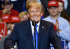 Donald Trump speaking at a rally, supporters in background.