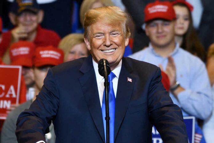 shutterstock_1155247306 Donald Trump speaking at a rally, supporters in background.