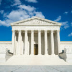 Supreme Court building with grand columns and steps under a blue sky