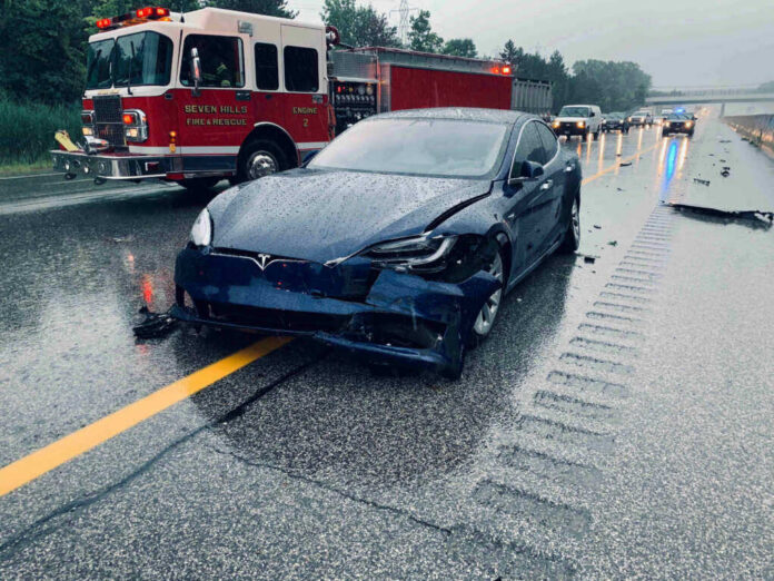 Car crash with a Tesla on a rainy highway.