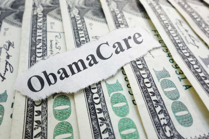 shutterstock_154183421 ObamaCare text over money background.