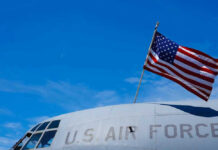 U.S. Air Force plane with American flag against sky.