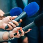 Danube Drops — Booby-Trapped Wrecks Emerge Reporters holding colorful microphones