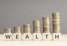 Hidden Millionaires Everywhere – Wait, 5 Million? Stacks of coins arranged next to wooden blocks spelling 'WEALTH'