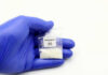 Hand in glove holding fentanyl packet with skull warning.