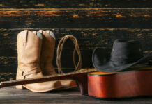 VIDEO: Country Ballad Dethrones Pop Star Cowboy boots, hat, and guitar on wooden surface.
