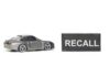 Recall Panic: Fuel Tanks Can Drop A miniature gray sports car next to a black sign that reads 'RECALL'