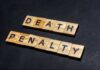 Child Torture Alleged — Death Penalty Sought Wooden letter tiles spelling DEATH PENALTY on a dark background