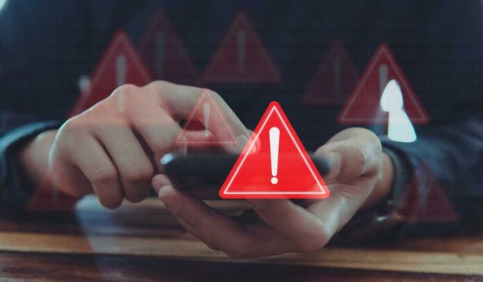 Emergency,Warning,Alert,Alarm,On,Smartphone,,Data,Network,Protection,,Virus Person using smartphone with red warning icons overlay