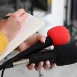 Mystery Blast Rocks Major Gas Giant Journalist holding two microphones while writing in a notebook