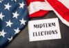 ELECTION: 80-Year-Old Steamrolls ‘New Blood’ Revolt American flag and a notebook with 'MIDTERM ELECTIONS' written on it