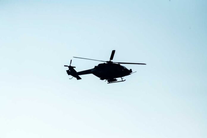 Silhouette of a helicopter flying against a light sky