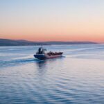 Chokepoint Chaos — Six Dead, Then This Cargo ship navigating through calm waters at sunset