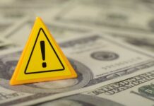 Gas Pump Gut-Punch Hits $100 Billion A yellow warning sign placed on a pile of dollar bills