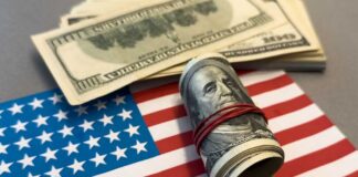 A roll of hundred dollar bills placed on an American flag