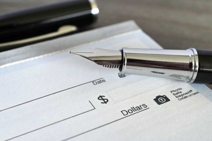 Fountain,Pen,On,A,Blank,Bank,Check,Cheque Close-up of a fountain pen poised over a blank check