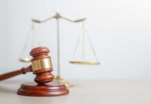 Judge Slams Doctor Who Tried To Kill Wife A wooden gavel in front of a balance scale symbolizing justice