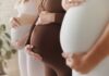Pregnant women standing side by side holding their bellies