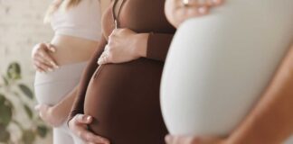 Pregnant women standing side by side holding their bellies