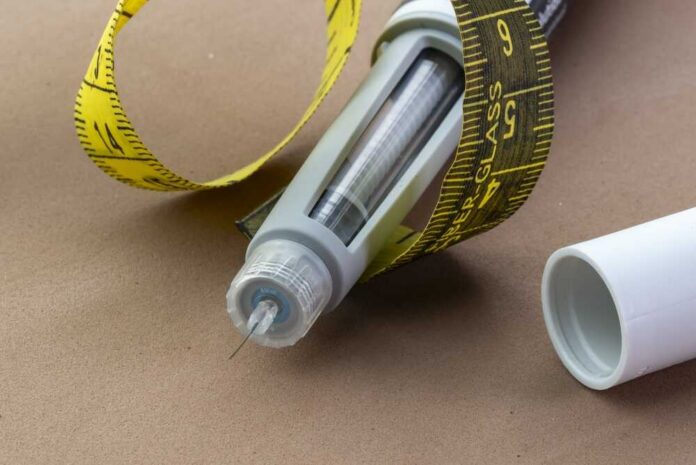 Insulin pen with needle and yellow measuring tape