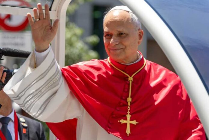 Catholic cleric in red vestments waves from a vehicle