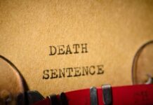 Typewriter typing the words death sentence on paper