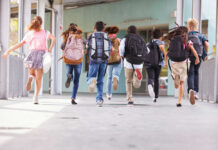 Pay Soars, Buses Still Empty – WHY? Children running with backpacks outside a school building.