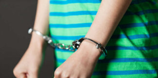 Person in striped shirt wearing handcuffs.