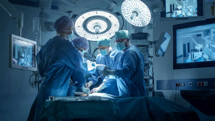 Josh Kline and Dontrelle Inman performing surgery with a medical team in an operating room