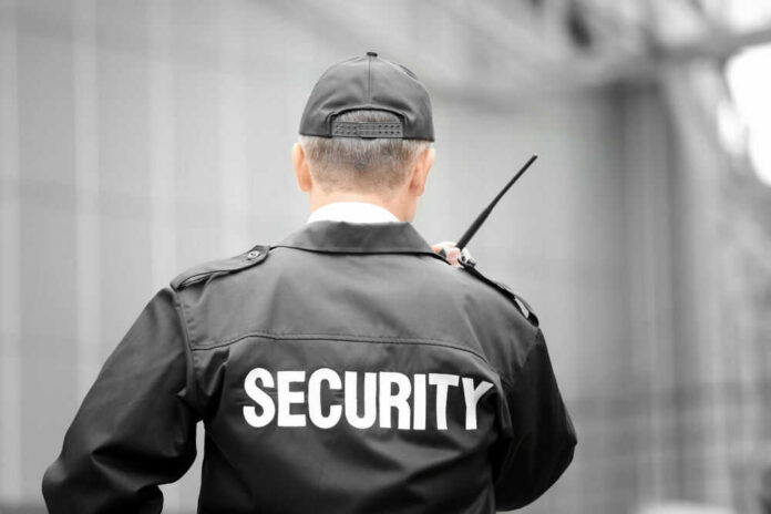 Security guard holding a radio, facing away.