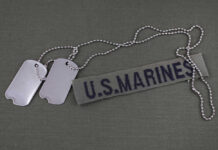 Dog tags beside a U.S. Marines name tape on olive fabric