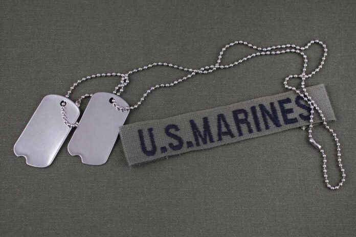 Dog tags beside a U.S. Marines name tape on olive fabric