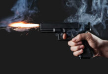 Cross-Country Hit? Superstar Singer Targeted A hand holding a gun with smoke and a flash from the muzzle