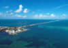 Aerial view of a coastal area with a long bridge extending over turquoise waters