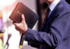 Televangelist Empire Crumbles – Jim Bakker Dead Man holding a Bible during a speech or presentation.