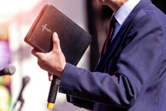 Man holding a Bible during a speech or presentation.