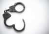 Seventh Arrest Shocks THIS City Open metal handcuffs on white background.