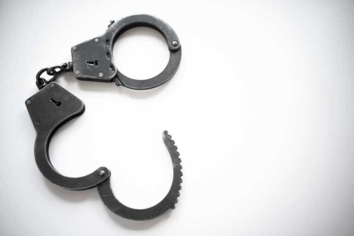 shutterstock_2116470560 Open metal handcuffs on white background.
