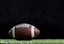 NFL Vet Dies Close-up of a football on a grassy field.