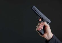 Hand holding a black semi-automatic pistol against a dark background