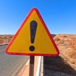 Bombshell: Night Predator Stalks Triangular warning road sign with exclamation mark on a rural highway