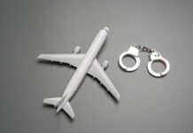Toy airplane with metal handcuffs on gray background