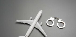 Toy airplane with metal handcuffs on gray background