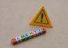 Raspy Voice Tied To Dementia? Colorful letter blocks spelling 'DEMENTIA' next to a warning sign