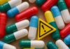 Colorful capsules scattered around a yellow warning sign