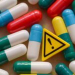 Deadly Gas-Station Pills Exposed Colorful capsules scattered around a yellow warning sign