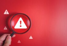 Magnifying glass over a warning triangle on a red background